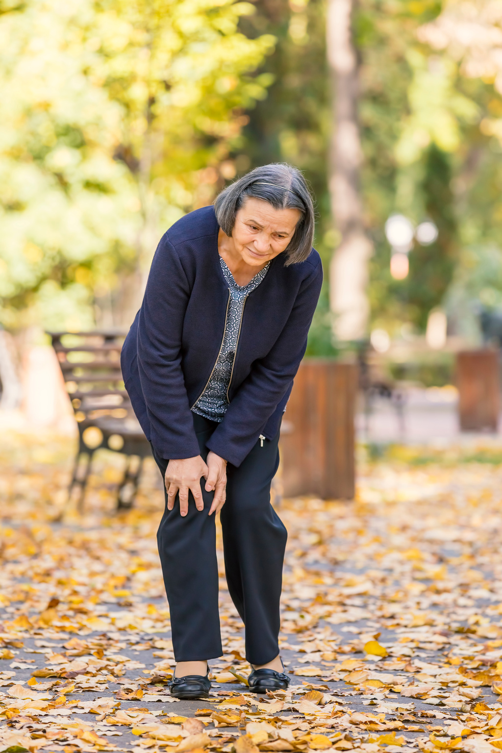 Senior woman having knee pain in park